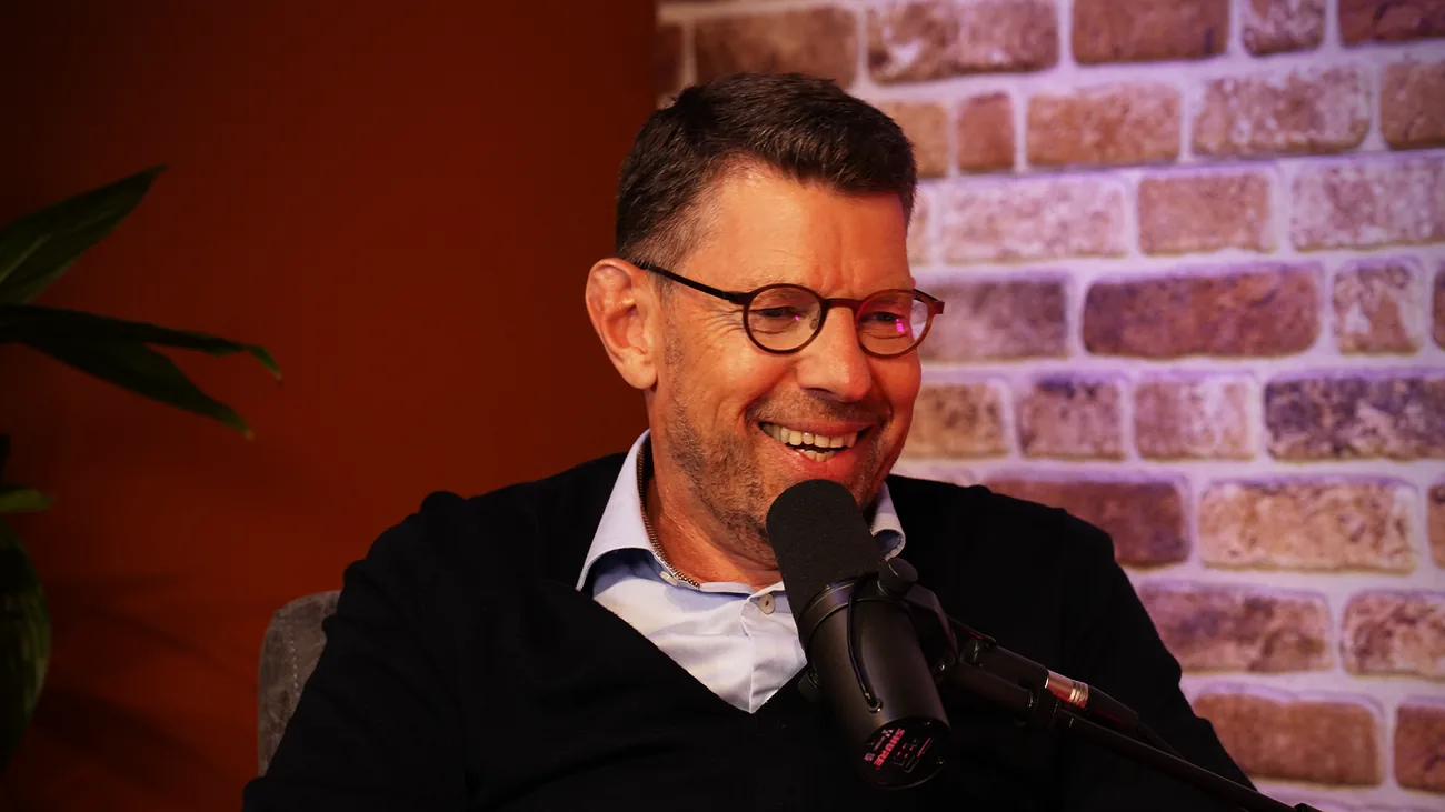 Gast lacht achter de microfoon in de studio van Podcast Studio Westland