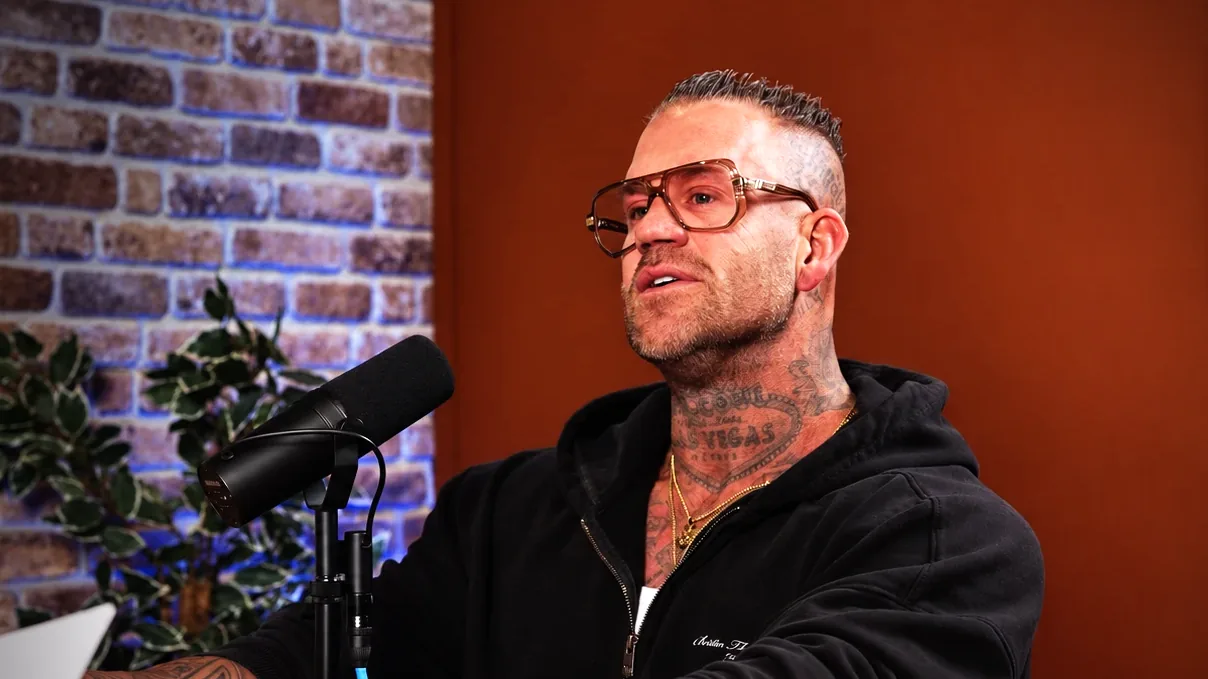 Gast met tatoeages en een bril vertelt achter de microfoon in de studio