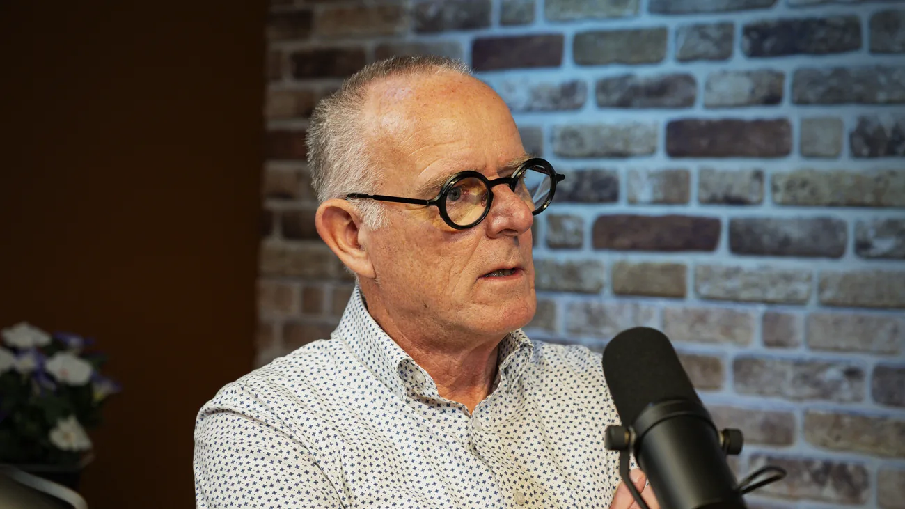 Gast met bril in gesprek achter de microfoon in de studio
