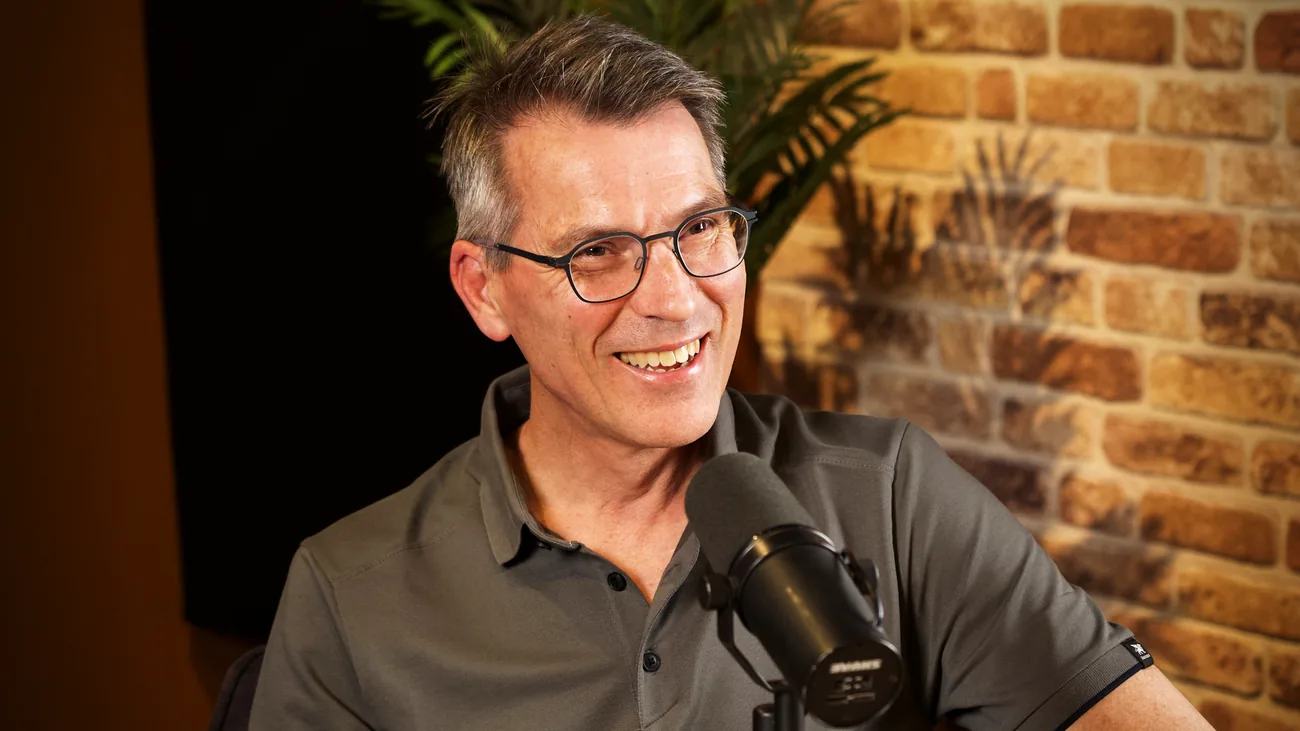 Gast in poloshirt lacht achter de microfoon in de studio