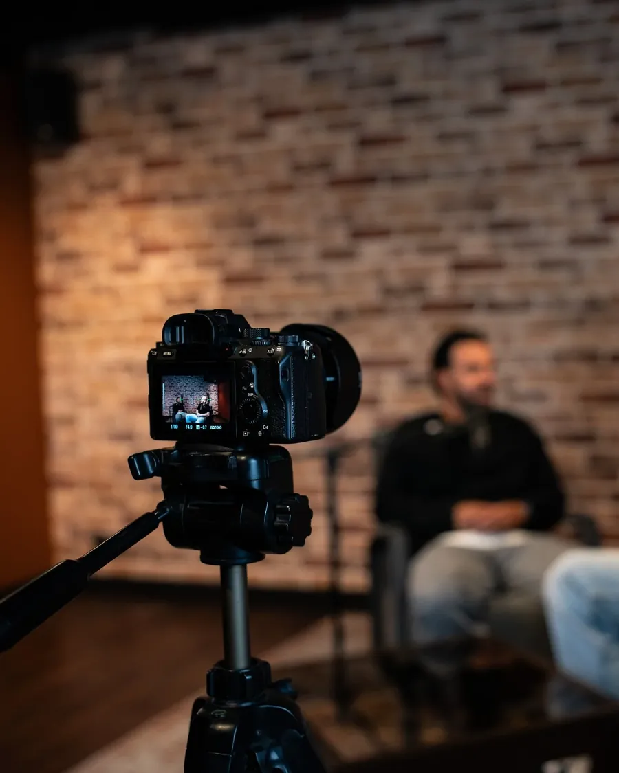 Een camera op statief filmt twee gasten aan tafel in onze studio